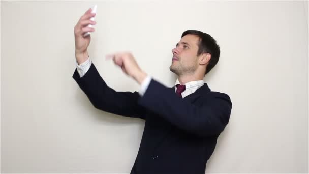 Joven hombre de negocios guapo haciendo selfie, sonriendo y agitando la mano . — Vídeos de Stock