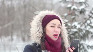 Güzel genç kız kış parkta yürürken onu smartphone içinde sosyal ağlar üzerinden saygısız.