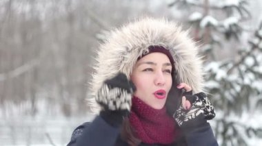 Genç güzel kız aktif olarak duran bir kış parkta onun smartphone cep telefonu ile konuşmak.