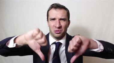 Genç yakışıklı işadamı başparmak aşağı iki el ile onun hoşnutsuzluğunu ifade gösterir.