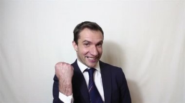 Yakışıklı genç işadamı aktif sevinç ifade eder, eliyle bir jest yapar ve 