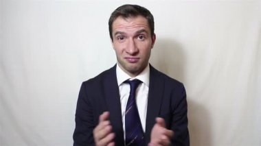 Yakışıklı genç adam alaycı bir şekilde gülümseyip ellerini çırpıyor..