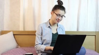 Çekici bir kız evde yatakta oturmuş onu laptop üzerinden mesaj bir mesaj atıyor.