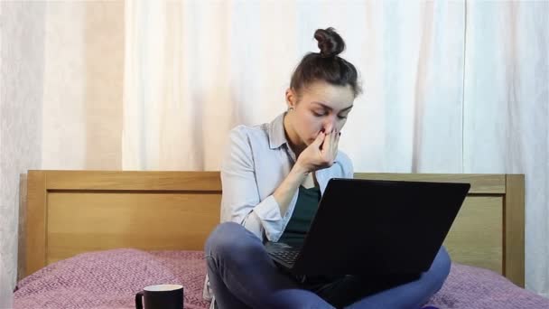 Een jong mooi meisje haar ogen van vermoeidheid op haar laptop werken wrijven. — Stockvideo