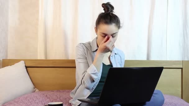 Молодая красивая девушка трёт глаза от усталости, работая над своим ноутбуком. . — стоковое видео