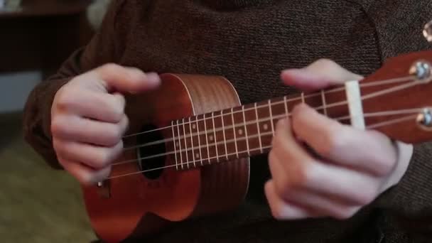 Handen van een jonge vent spelen de ukulele. — Stockvideo