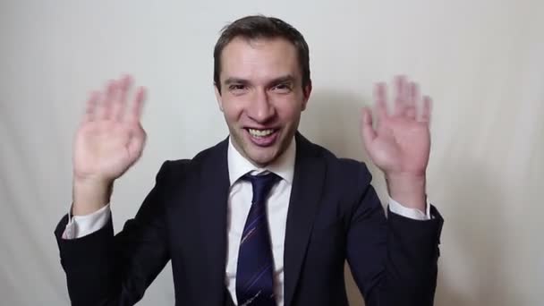 Giovane bellissimo uomo d'affari in abito blu sorridente e agitando la mano saluta i clienti . — Video Stock