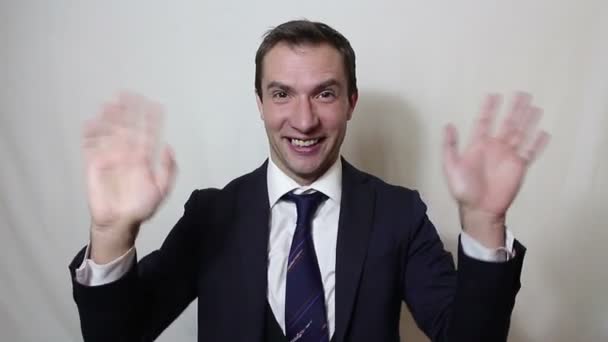 Giovane bellissimo uomo d'affari in abito blu sorridente e agitando la mano saluta i clienti . — Video Stock