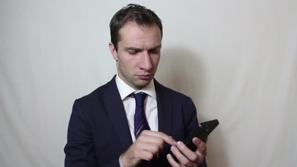 Νεαρός όμορφος επιχειρηματίας βλέπει ειδήσεις στο smartphone του. — Αρχείο Βίντεο