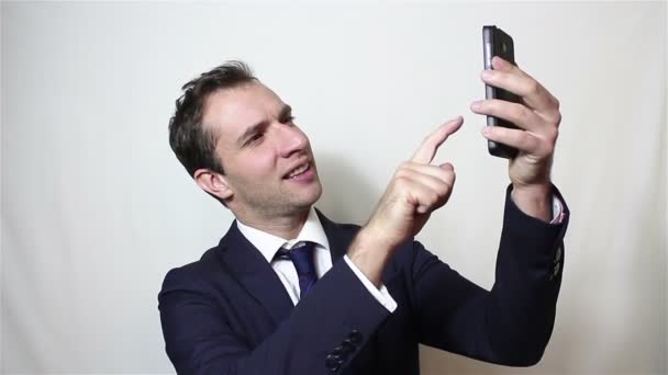 Ung snygg affärsman gör selfie, ler och vinkar handen. — Stockvideo