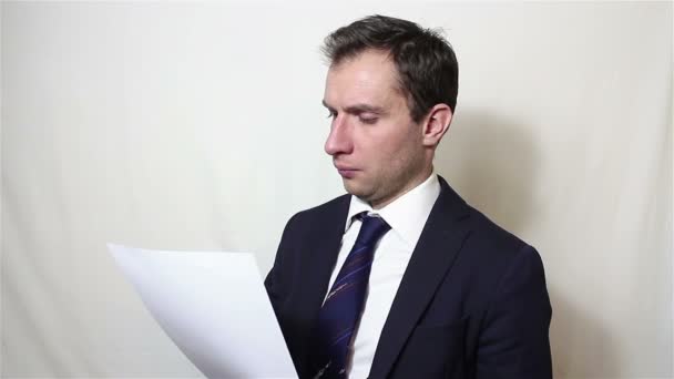 Ein junger gutaussehender Geschäftsmann nimmt ein Blatt Papier mit einem Vertrag und liest es sorgfältig. — Stockvideo