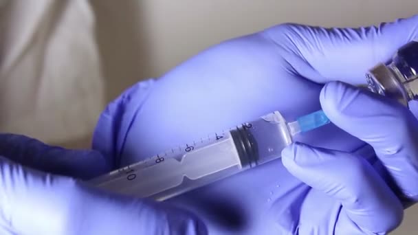 Artsen handen injecteren de oplossing in een ampul van vaccin met een spuit, mengen van de medicatie, voorbereiden van de injectie van de patiënt. — Stockvideo