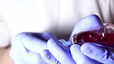 Doktorlar eller bir enjeksiyon hasta hazırlama kırmızı bir aşı ile şırıngaya doldur.