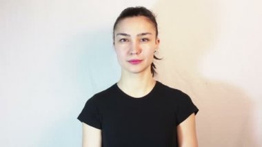 Siyah bir tişört gülümser güzel bir genç kız ve kadınlar kameraya doğru bakarken kaşlarını yükseltir.