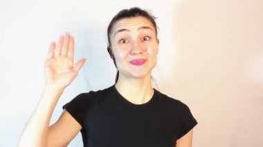 Genç ve çekici bir kız gülümseyip el sallıyor..