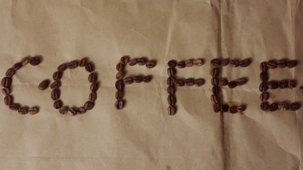 Die Aufschrift "Kaffee" auf Kraftpapier, auf das die Kaffeebohnen fallen. — Stockvideo