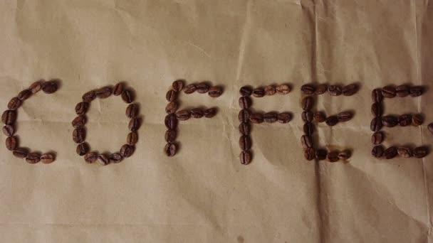 Nápis "Káva" se nachází na krafovém papíře, na kterém se zrnka kávy padá. — Stock video