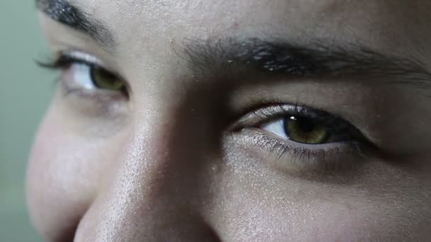 Uma menina bonita com grandes olhos verde-marrom olha coquettishly para a câmera . — Vídeo de Stock