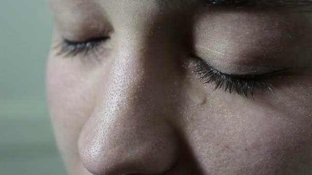 Hermosa joven está triste y llorando. Una lágrima rueda de los ojos verdes en la mejilla. Ojos de cerca . — Vídeos de Stock