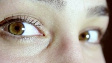 Güzel bir genç kızın yeşil-kahverengi gözleri. Kız kameraya bakar, göz kırpar ve gözlerini yuvarlar..