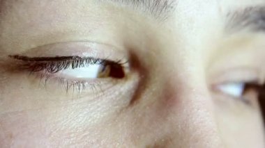 Güzel bir genç kızın yeşil-kahverengi gözleri. Kız kameraya bakar, göz kırpar ve gözlerini yuvarlar..