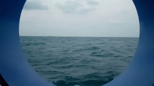 Vista dell'oceano dall'oblò della nave in marcia. Una nave nell'oceano è visibile dall'oblò di una nave da crociera . — Video Stock