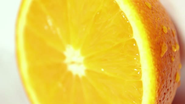 Drops of water flow down a juicy ripe orange. Orange on a white background. — Stock Video