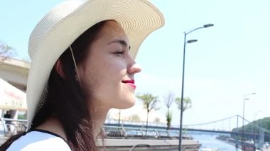 Beyaz şapkalı genç çekici kız, bakışlarını gökyüzüne doğru kaldırır ve güneşten gözlerini kısardı. Beyaz şapkalı güzel bir genç kızın portresini kapatın.