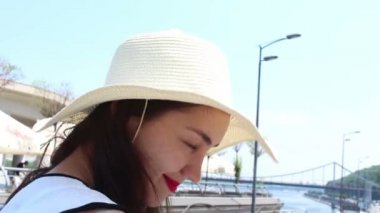 Beyaz şapkalı genç çekici kız, bakışlarını gökyüzüne doğru kaldırır ve güneşten gözlerini kısardı. Beyaz şapkalı güzel bir genç kızın portresini kapatın.