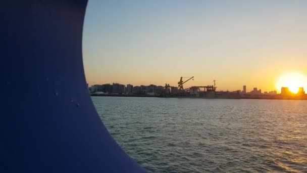 Zonsondergang over de Oceaan en de zeehaven. Uitzicht op de zonsondergang en de Oceaan door de patrijspoort van het schip. Uitzicht op de Oceaan en de stad vanuit de cabine van een cruiseschip. — Stockvideo