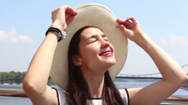 Retrato de cerca de una hermosa joven con un sombrero blanco. Joven chica atractiva en un sombrero blanco, eleva su mirada al cielo y entrecerran los ojos del sol . — Vídeo de stock