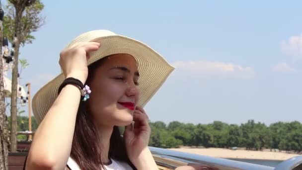 Close up portrait A beautiful young girl in a white hat looks into the camera and smiles. A young attractive girl in a white hat, raises her gaze to the sky and squints from the suns rays. — Stock Video