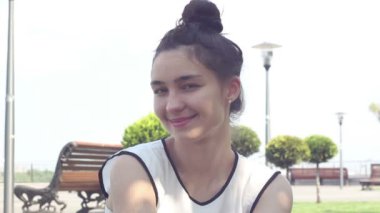 Yakın portre Beyaz bir t-shirt güzel genç kız kameraya bakar, gülümsüyor ve bir Hava öpücük gönderir.