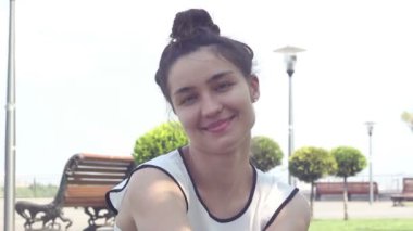 Yakın portre Beyaz bir t-shirt güzel genç kız kameraya bakar, gülümsüyor ve bir Hava öpücük gönderir.