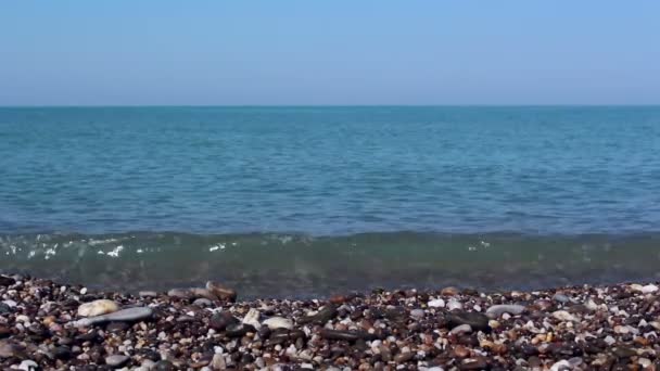 Vista sul mare e sulla costa rocciosa, con ciottoli marini. Mare con acque azzurre limpide.Mare surf sulla riva rocciosa . — Video Stock