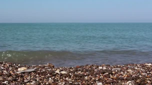 Vista do mar e da costa rochosa, com seixos do mar. Mar com água azul clara.Mar surfar na costa rochosa . — Vídeo de Stock