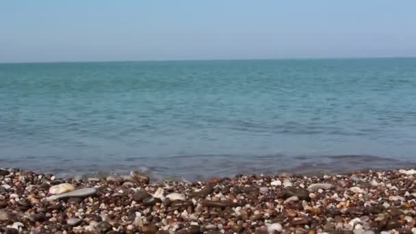 Uitzicht op de zee en de rotsachtige kust, met zee kiezels. Zee met helder blauw water. Sea Surf op de rotsachtige kust. — Stockvideo