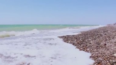 Fırtınalı deniz ve sahil manzarası. Deniz dalgaları çakıl bir sahilde yuvarlanıyor. Denizde fırtına.