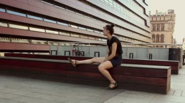 Genç ve güzel bir kız bir ofis binasının arka planında dinleniyor..