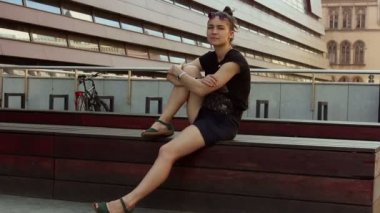 Genç ve güzel bir kız bir ofis binasının arka planında dinleniyor..