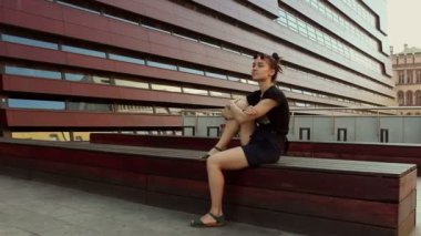 Genç ve güzel bir kız bir ofis binasının arka planında dinleniyor..