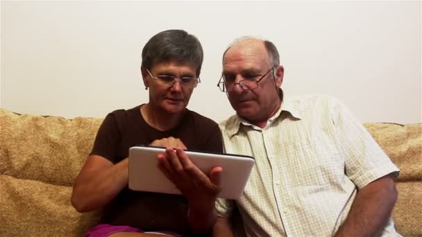 Attractive adult woman and adult man view photos on a tablet pc. — Stock Video