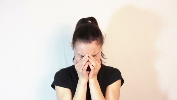 Young beautiful girl is very upset. The face expresses disappointment and sadness. The girl covers her face with her hands and cries. — Stock Video