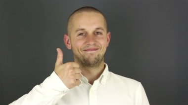 Komik yakışıklı adam gülümser ve parmağını kaldırır. Gri arkaplanda portre.