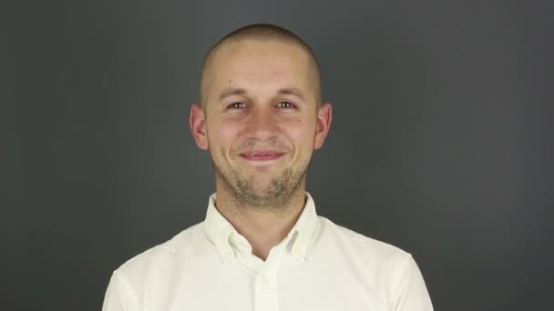 A funny handsome guy says yes and nods affirmatively. Portrait of a young guy, he says the word yes and nods in the affirmative. Portrait on a gray background.