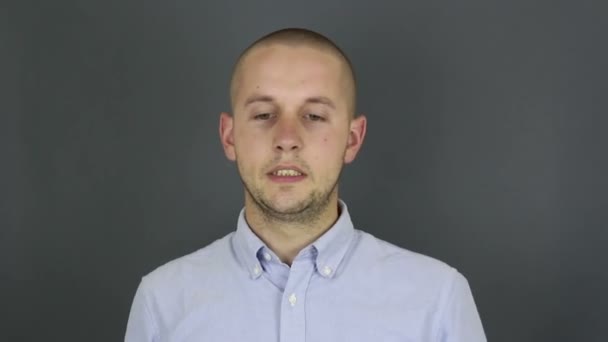 Un joven guapo se frota la frente con la mano de la fatiga. Un joven con una camisa blanca borra el sudor de su frente después de un largo trabajo . — Vídeos de Stock