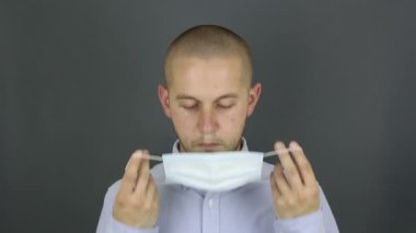 Genç yakışıklı bir adam tıbbi maske takıyor. Beyaz gömlekli genç bir adam koruyucu bir tıbbi maske takıyor..