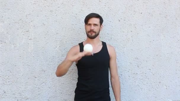 Mladý atraktivní chlap žongluje se třemi bílými koulemi. Mladý muž trénuje žonglování dovednosti. — Stock video