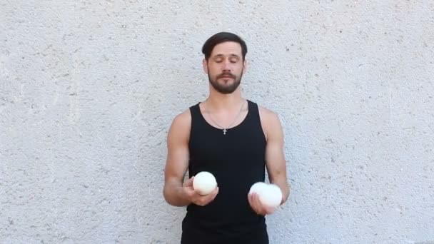 Un joven atractivo hace malabares con tres bolas blancas. Joven chico está entrenando malabares habilidades . — Vídeo de stock