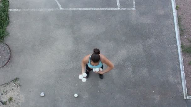 Profesionální žonglér s bílými koulemi. Atraktivní dívka žonglér trénuje její žonglérské dovednosti. Profesionální cirkusová herečka žongluje s bílými koulemi na ulici. — Stock video